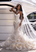 A woman models an elaborate white lace mermaid wedding gown with a long sheer veil, tiara, and statement jewelry in front of a white yacht. Gold text overlays read 'Custom Designs by Inna Elsie' and 'INNA ELSIE'.