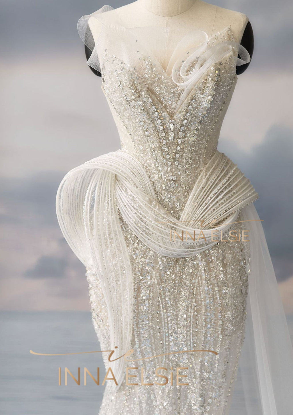 Elegant white beaded evening gown on a mannequin with a blurred background