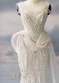 Elegant white beaded evening gown on a mannequin with a blurred background
