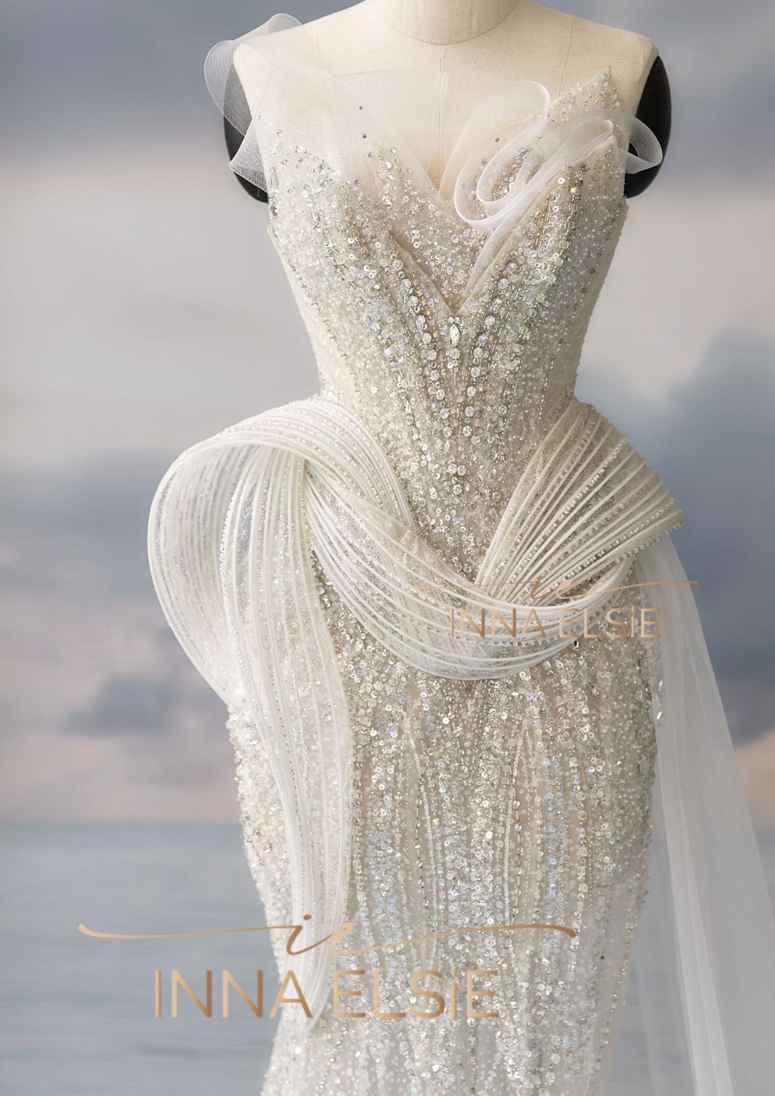 Elegant white beaded evening gown on a mannequin with a blurred background