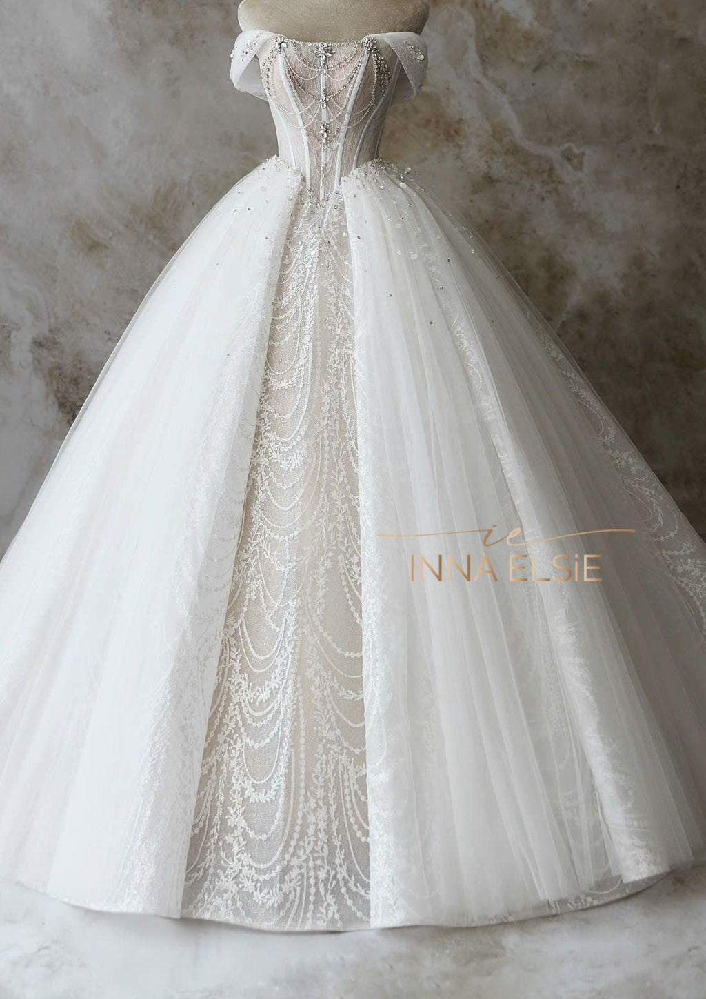 Elegant white wedding dress with intricate detailing on a neutral background