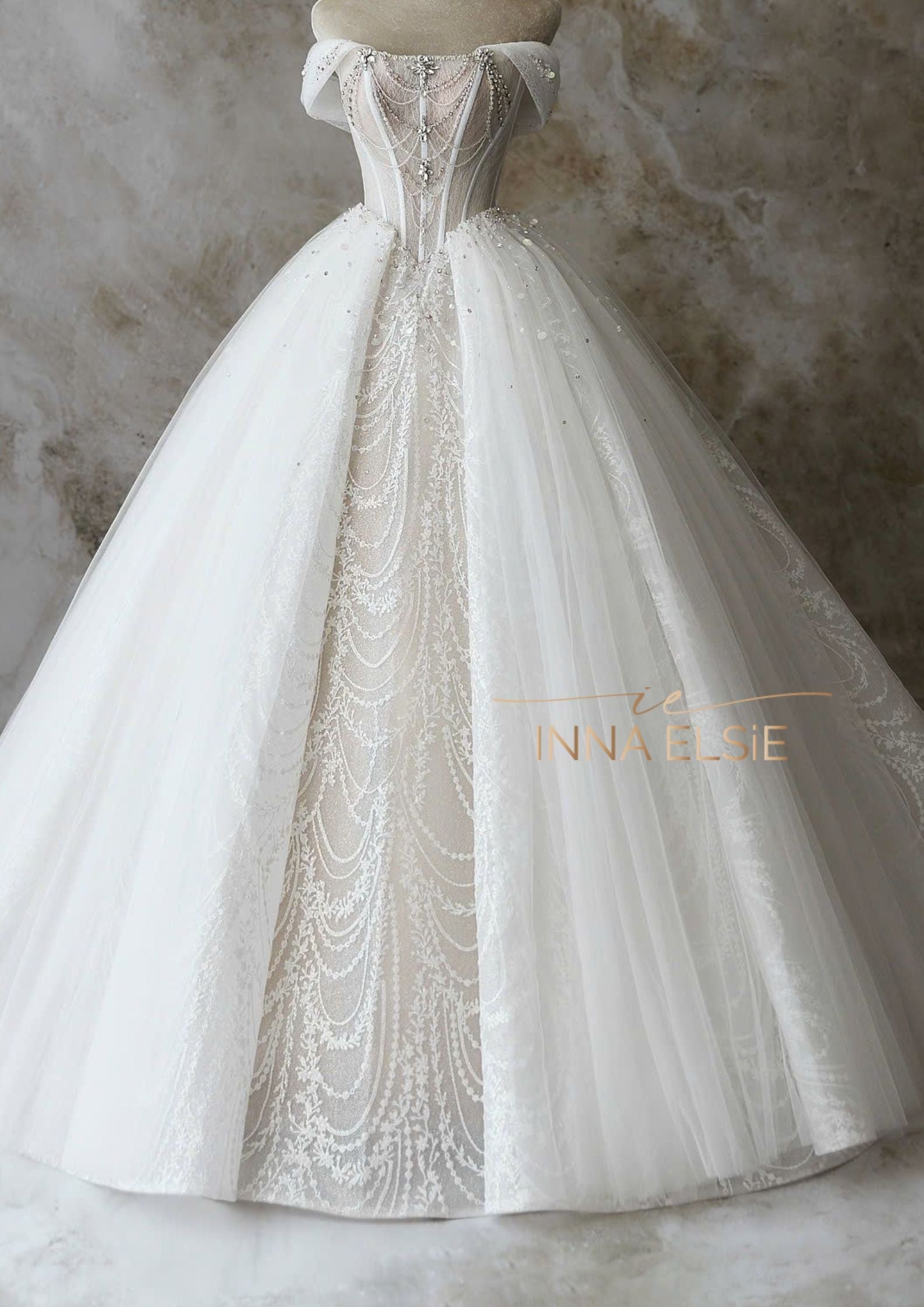 Elegant white wedding dress with intricate detailing on a neutral background