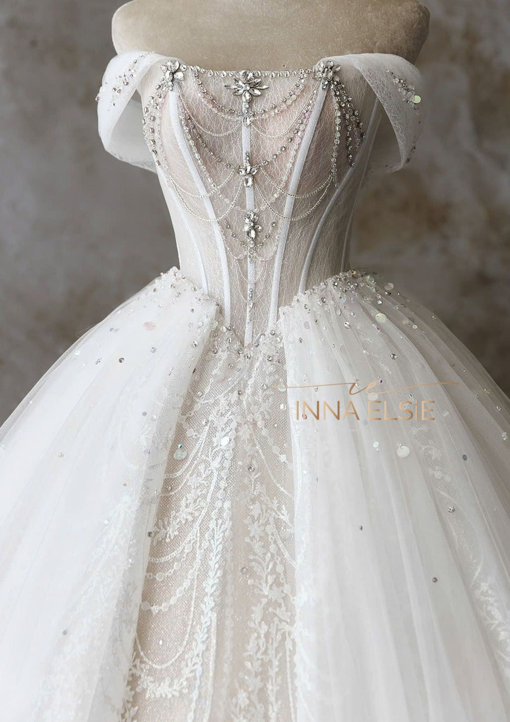 Elegant white wedding dress with intricate detailing on a mannequin against a neutral background.